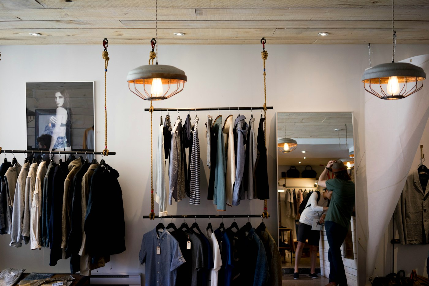 Clothing boutique with garments on hanging rails under pendant lights